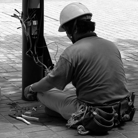 an electrician wearing a tool belt, installing electrical wiring